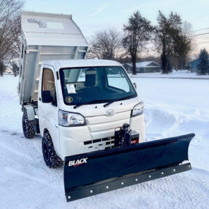 Mini dump truck with snow plow in driveway